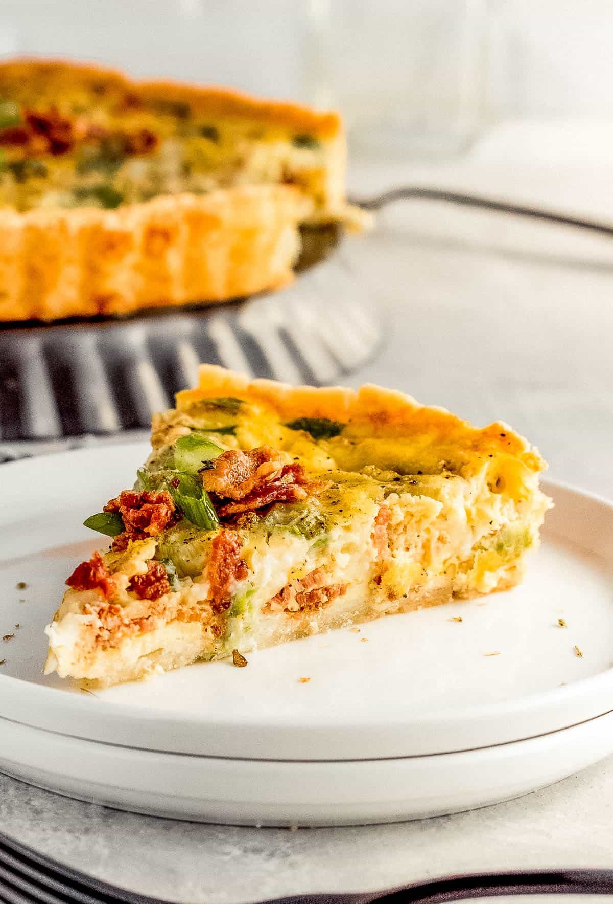 A Close-Up Shot of a Slice of Bacon Quiche Lorraine on a white plate