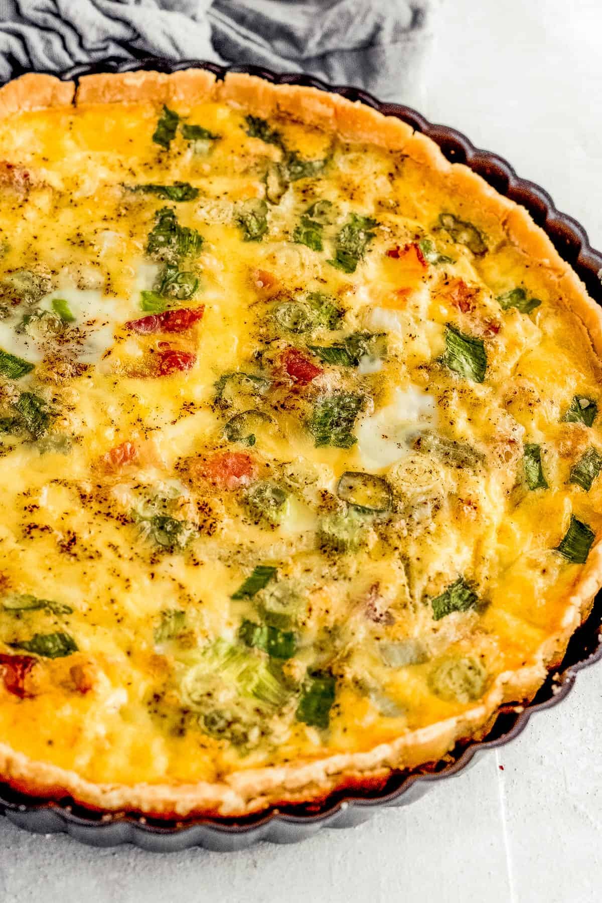 A Freshly Baked Quiche Lorraine Inside of a Black Quiche Pan