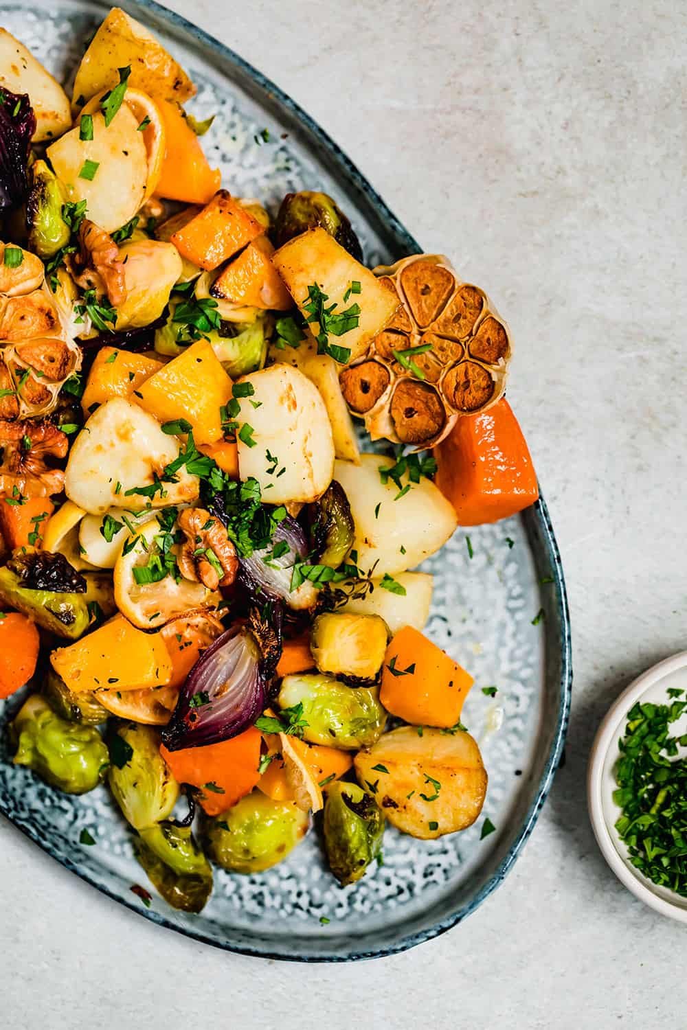 Golden roasted root vegetables on a blue serving platter.
