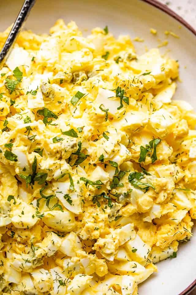 egg salad in a bowl topped with fresh parsley