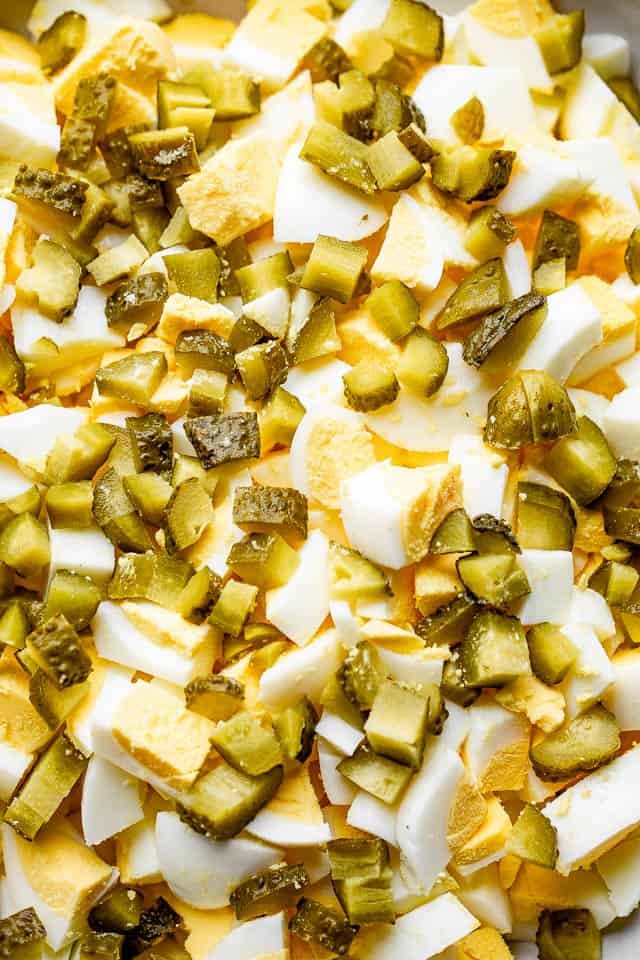 close up shot of chopped eggs and chopped pickles