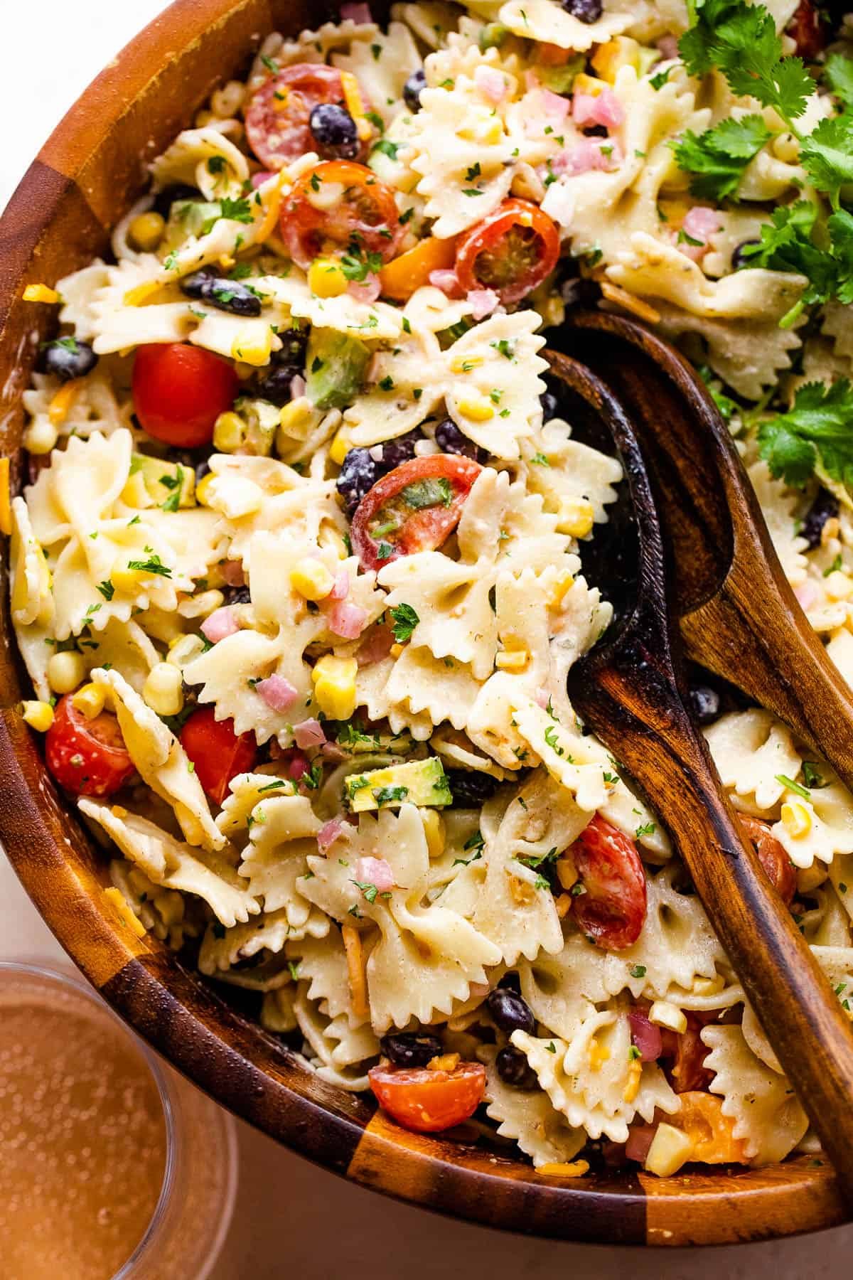 fiesta pasta salad in a wooden salad bowl with two wooden spoons
