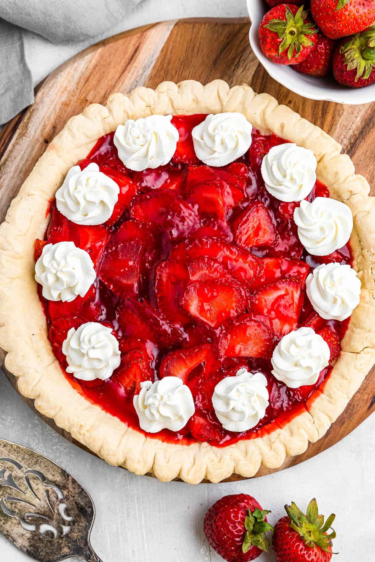 overhead shot of strawberry pie garnished with dollops of cream