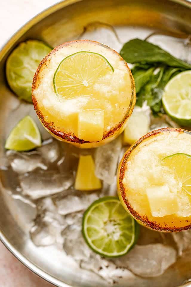 top view of frozen margaritas garnished with limes and pineapples