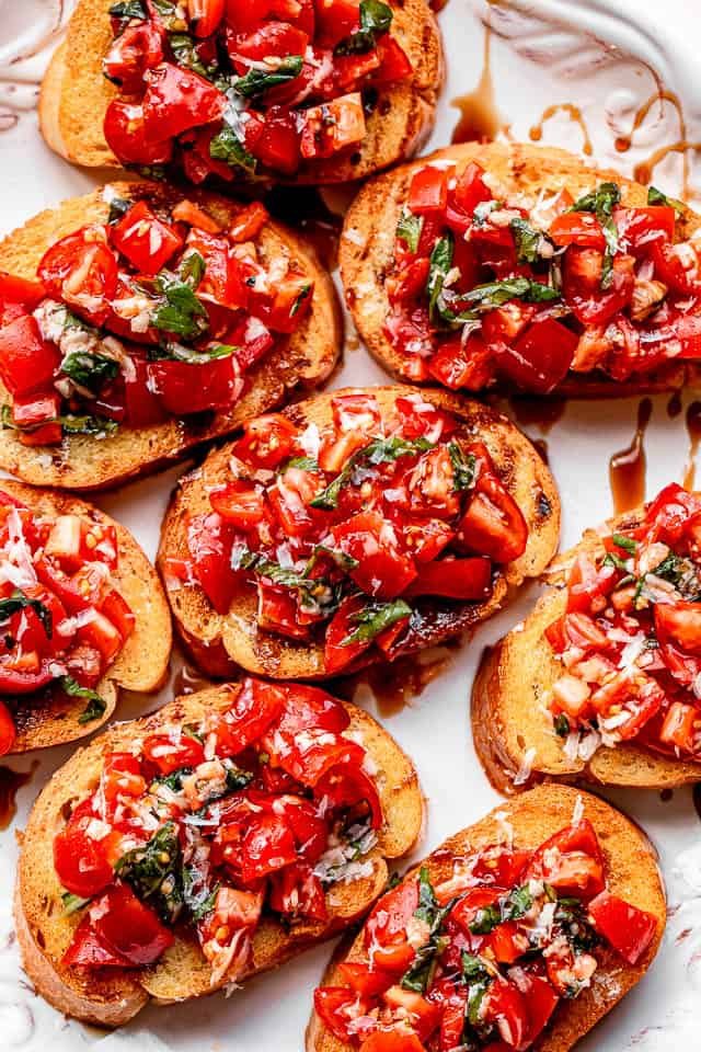 bread slices topped with tomato salad and served on a white platter