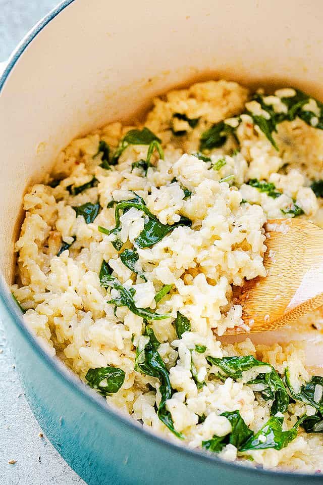 stirring rice and spinach with wooden spoon