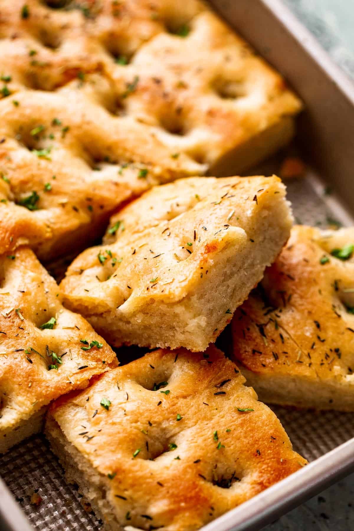 A large pan-sized loaf of focaccia, with one 4 squares cut away.