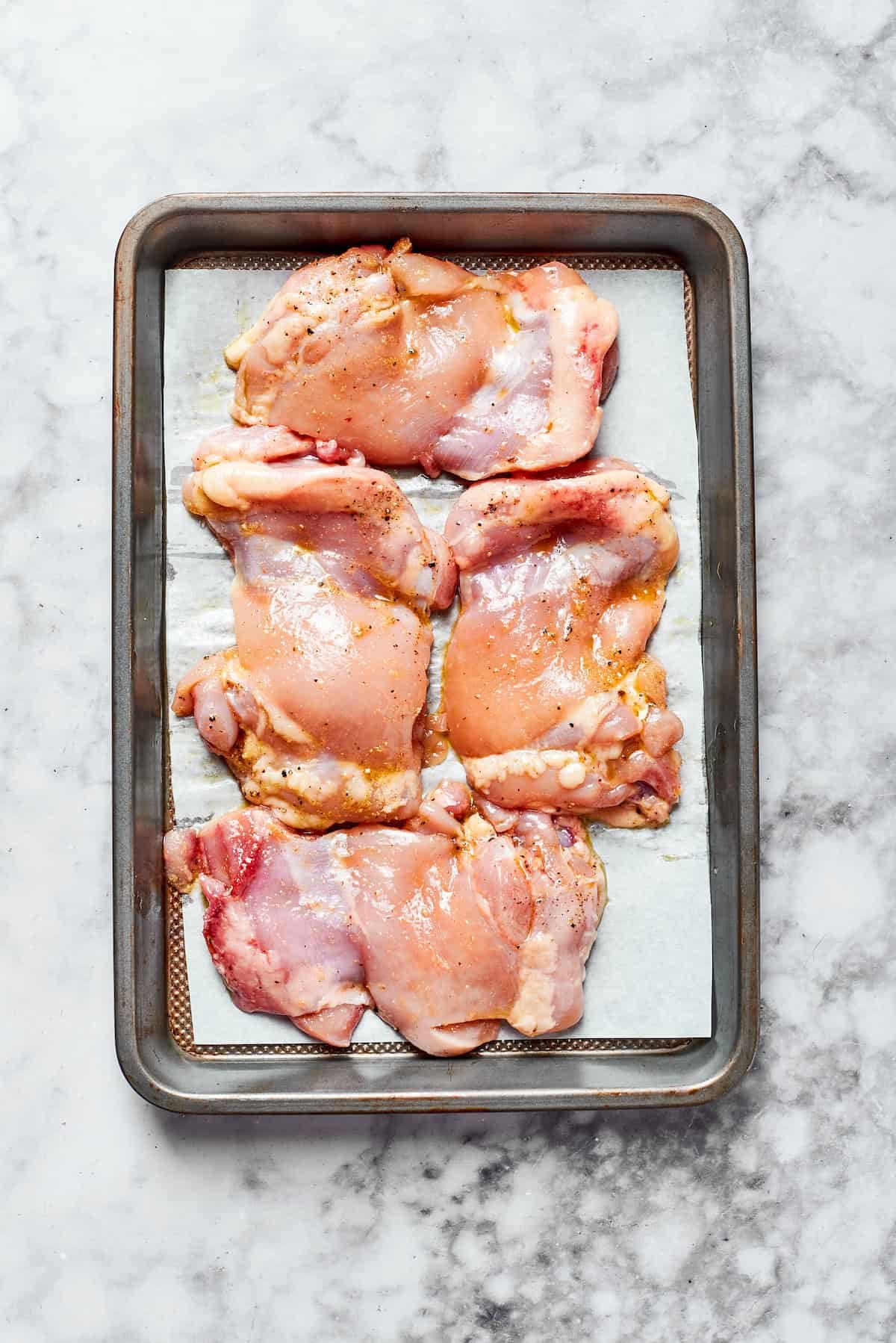 Raw chicken on a baking sheet ready to roast.