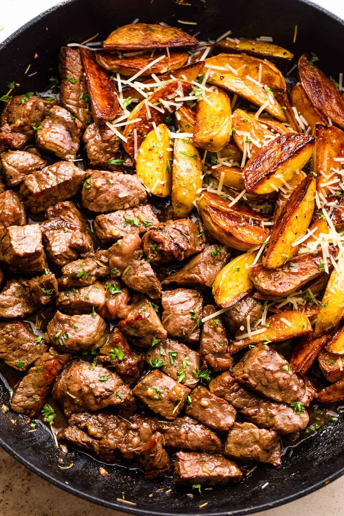 overhead shot of sirloin steak bites and quartered gold potatoes in a skillet