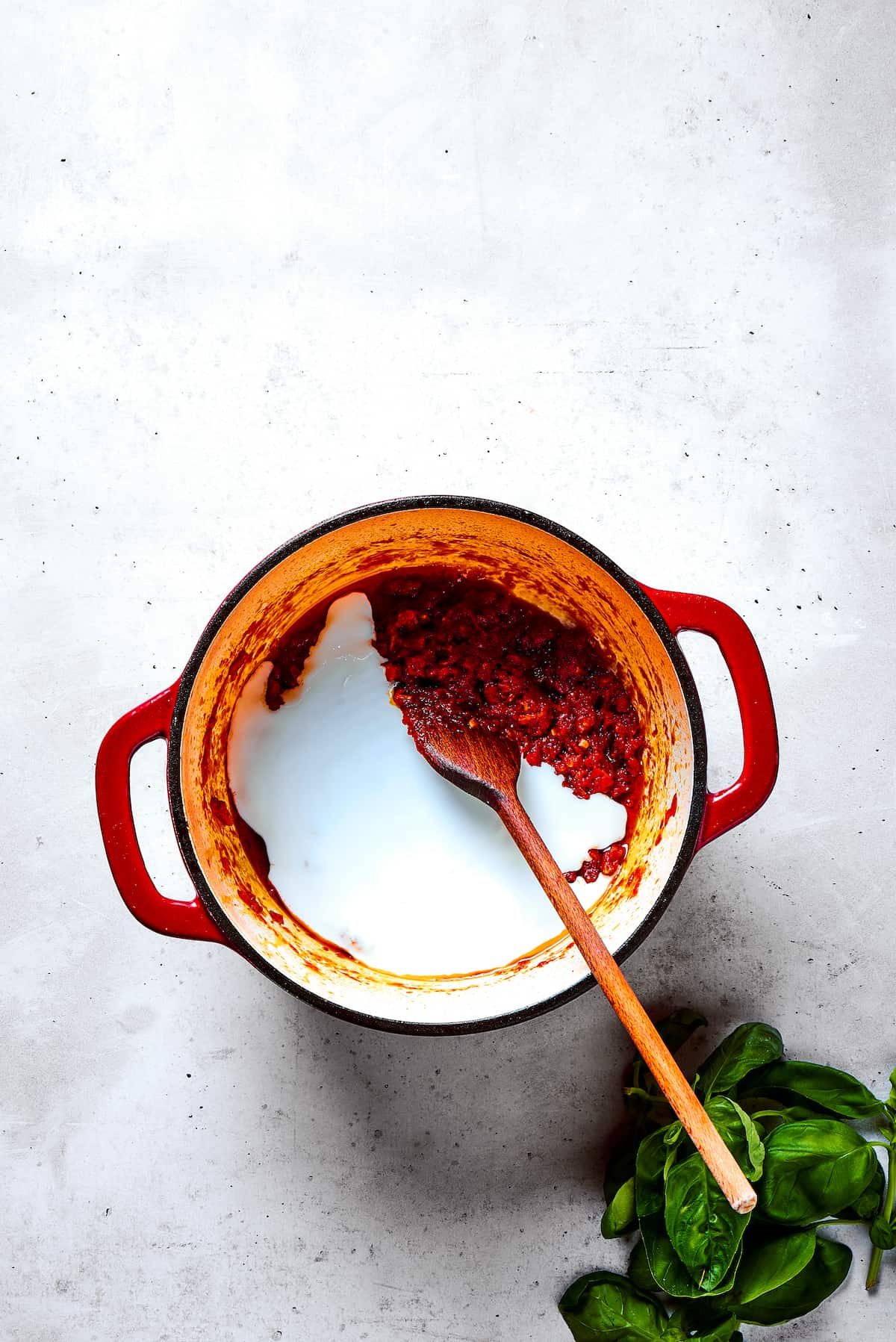 Stirring cream into a pot of sauce.