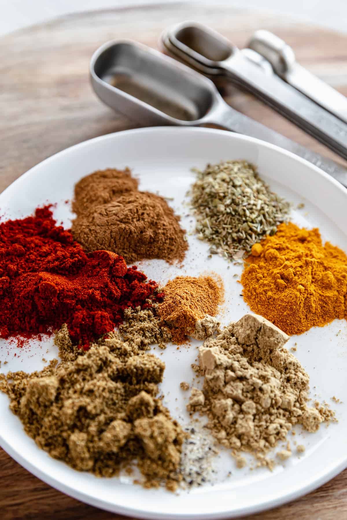 A Shallow Plate Containing Shawarma Spices Beside a Set of Metal Measuring Spoons