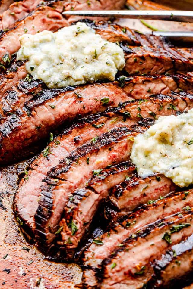close up side shot of sliced flank steak topped with compound butter