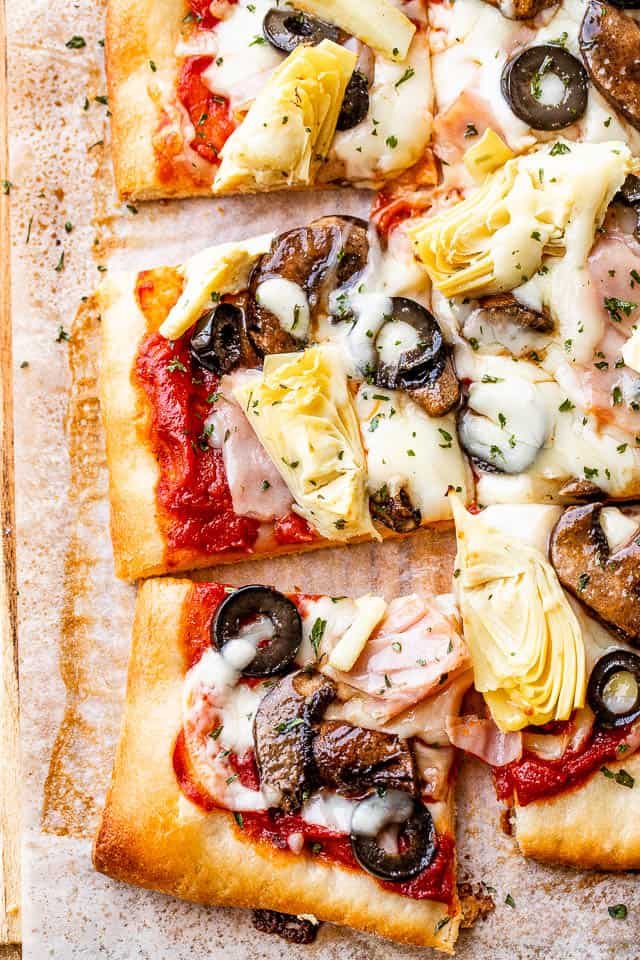 close up of capricciosa pizza topped with cheese, ham, mushrooms, and olives