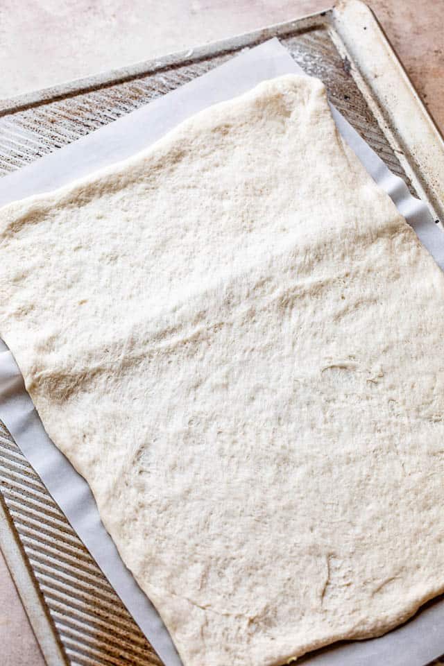 raw pizza dough on a baking sheet