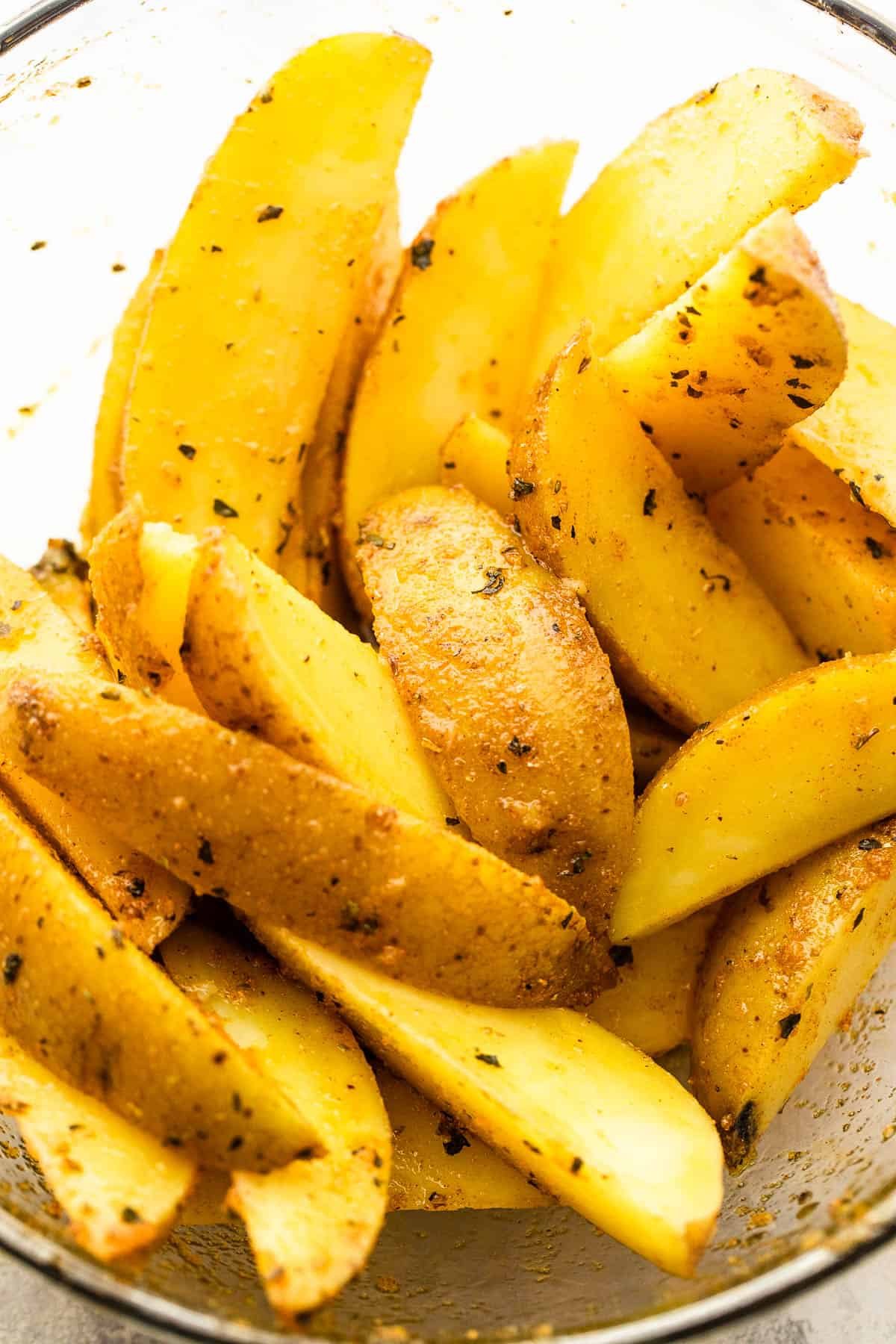 Cut up russet potatoes in a glass bowl.