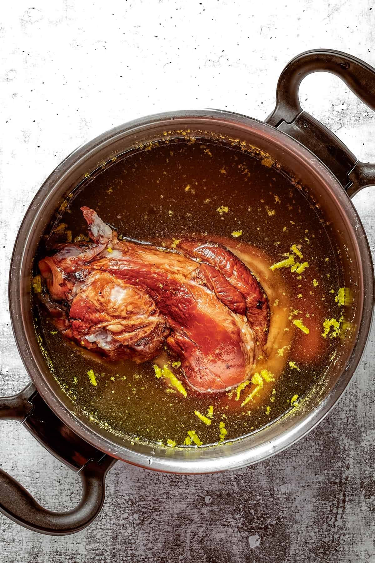 A stock pot filled with broth and a ham bone.