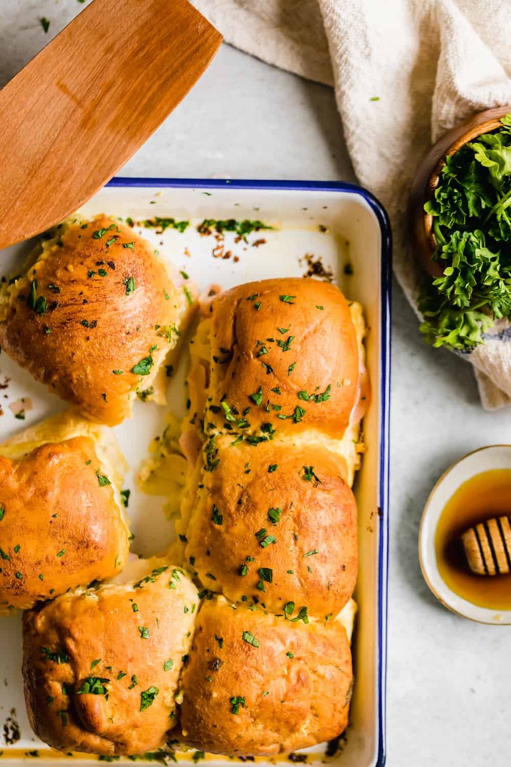 Six Hot Ham and Cheese Sliders Beside a Bowl of Parsley