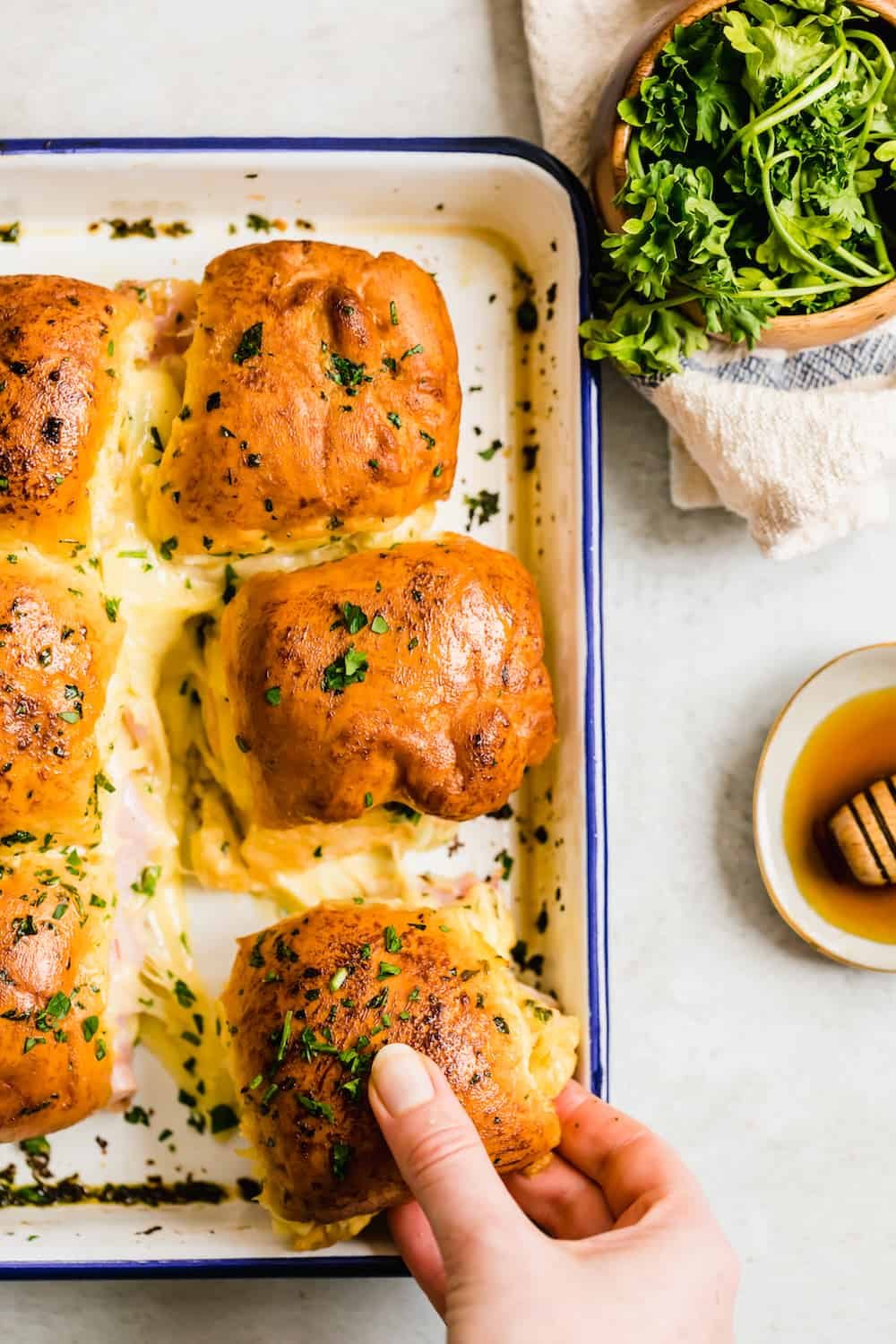 Six Cheesy Ham Sandwiches in a Navy Blue and White Baking Dish