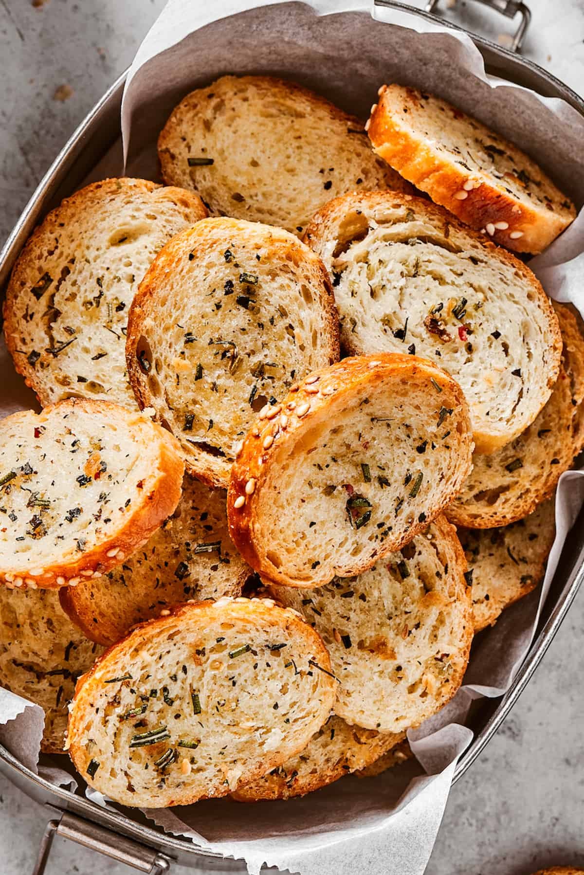 Seasoned and baked bagel chips in a metal tin.