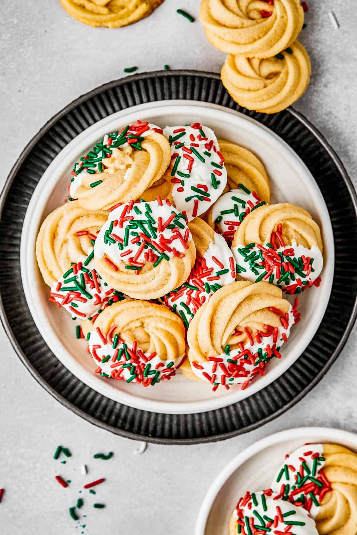 overhead shot of a small dessert plate stacked on top of several other plates, and piled with iced butter cookies.