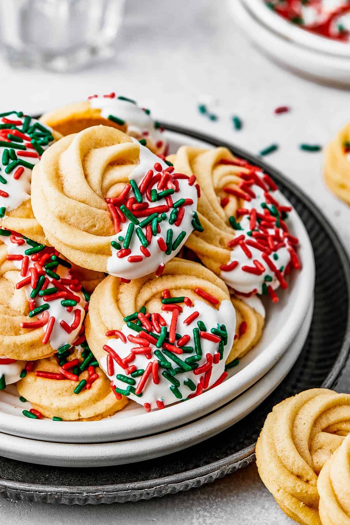 A small dessert plate stacked on top of several other plates, and piled with iced butter cookies.
