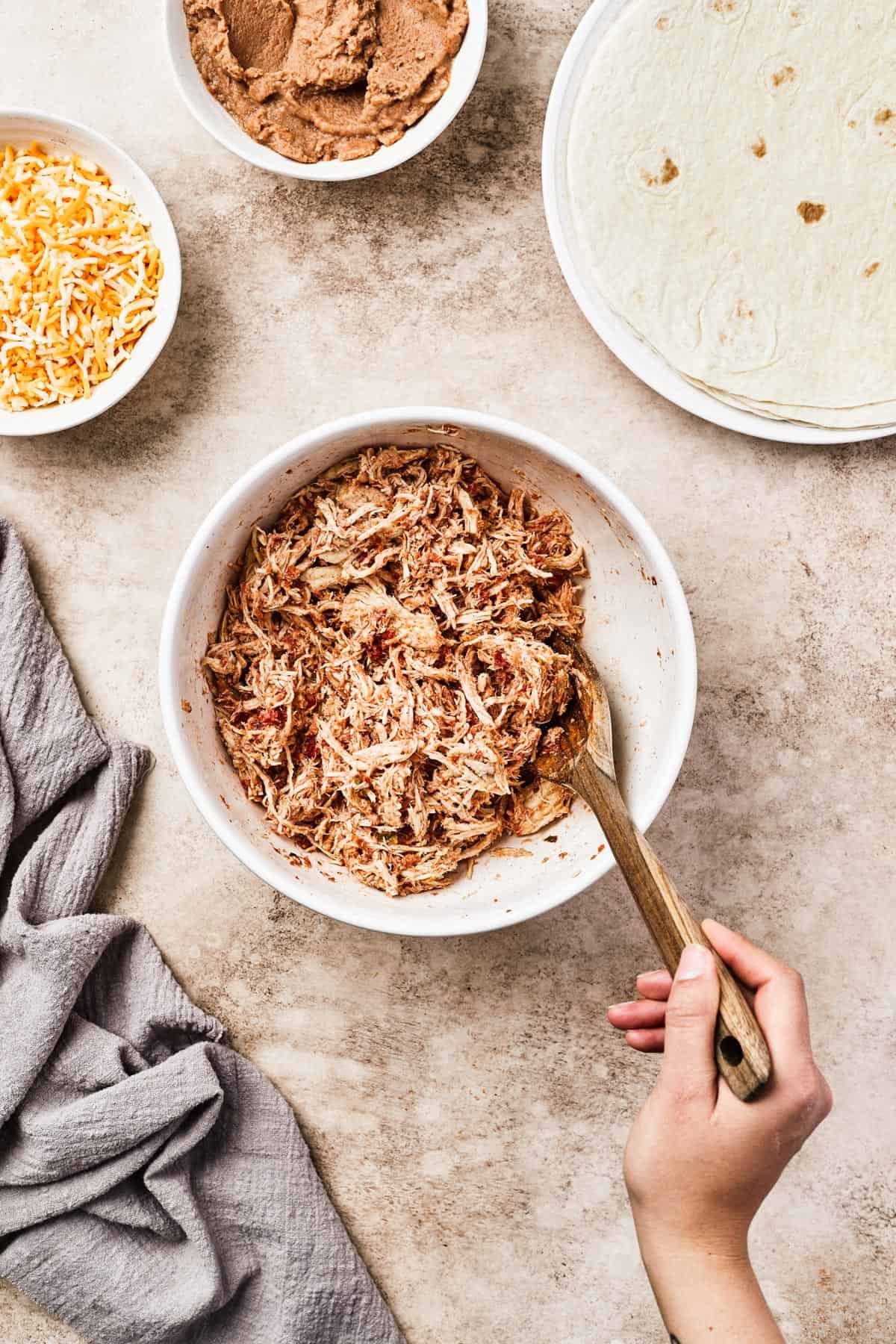 Shredded chicken mixed with salsa and spices in a white bowl.