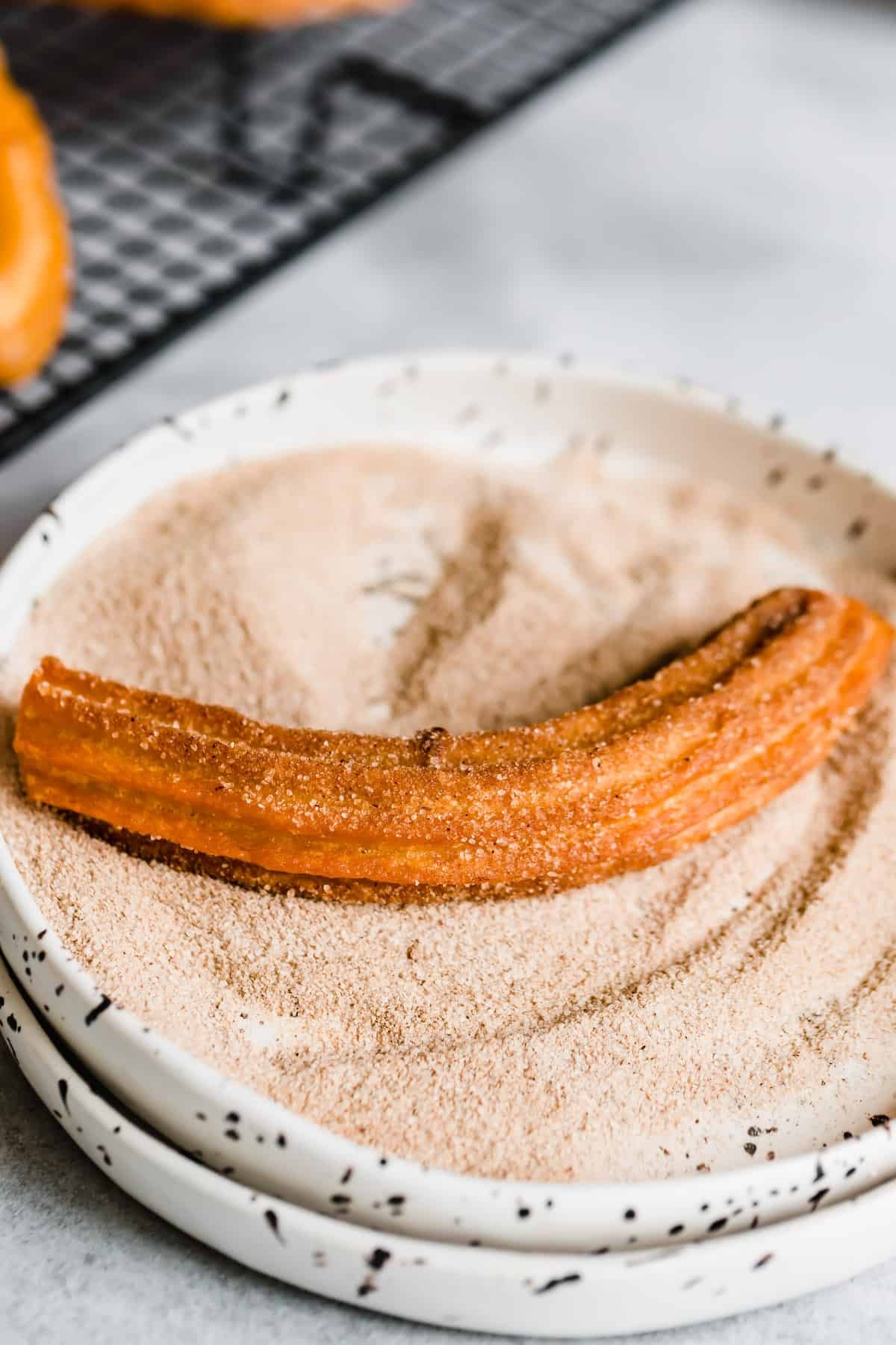 A Churro Inside a Shallow Bowl Filled with Cinnamon Sugar