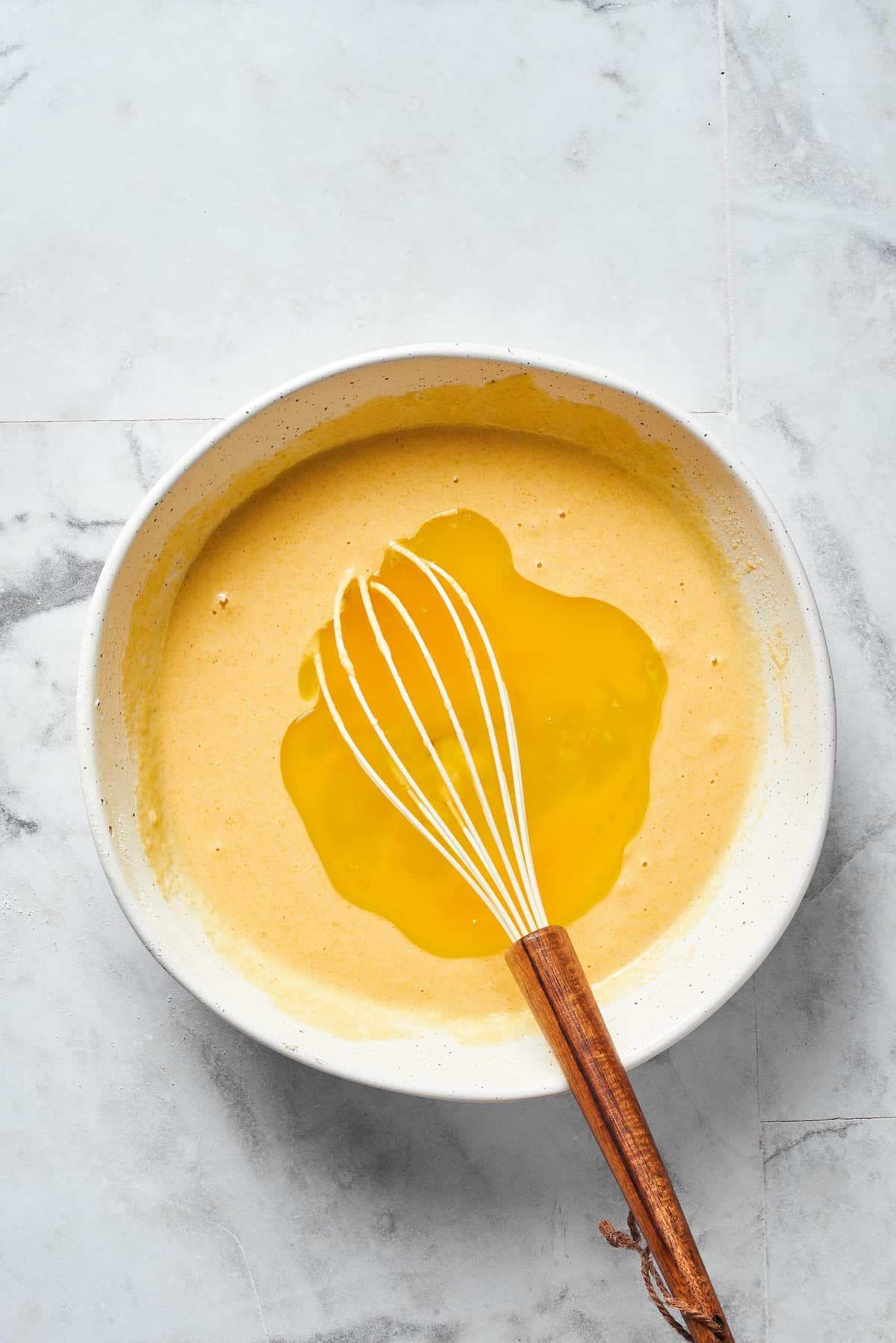 Making a well in dry ingredients using a whisk.