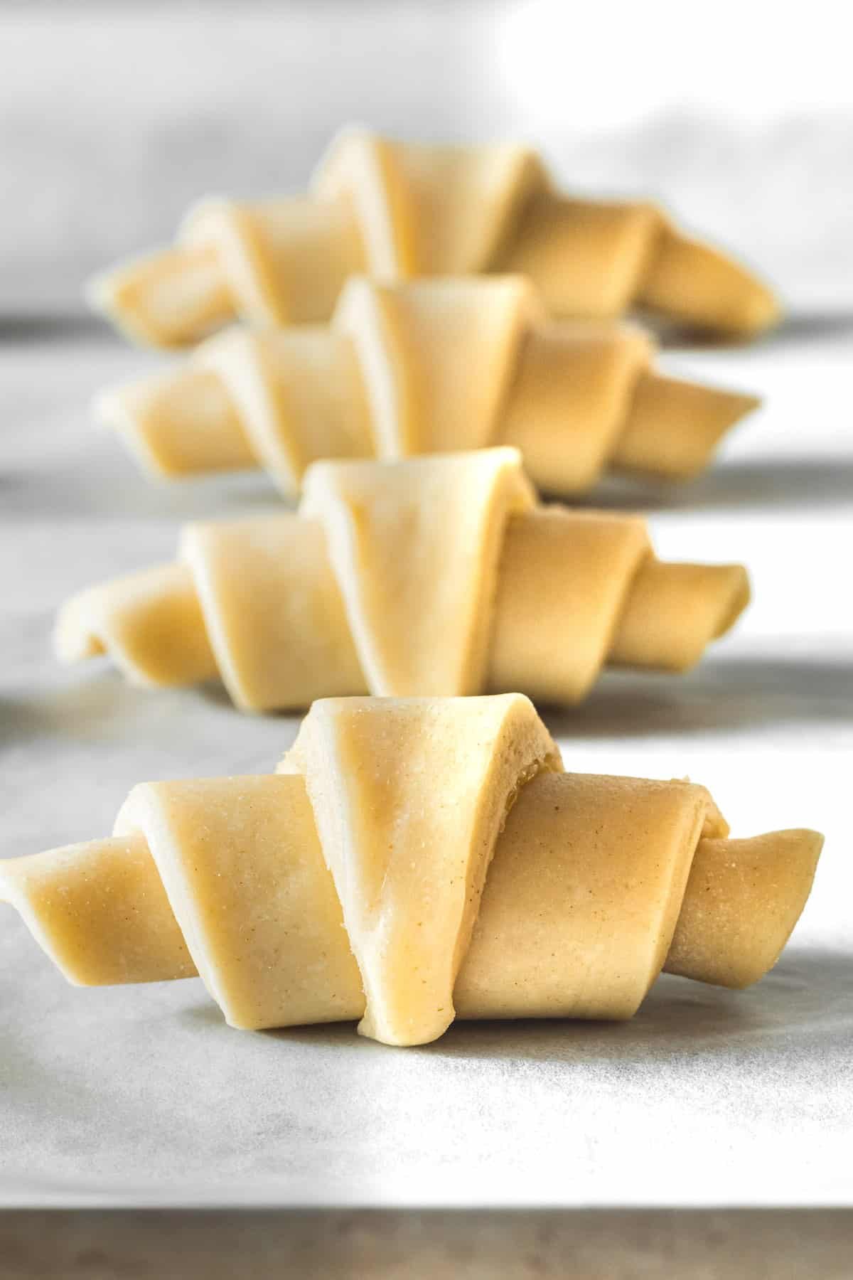 Raw dough rolled into crescents on a baking sheet.