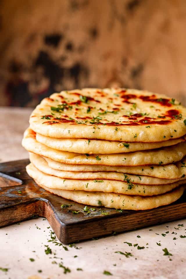 Stack of homemade flatbread on a wooden board.