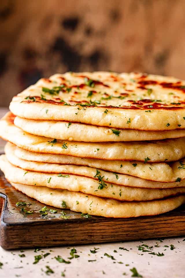 Stack of homemade flatbread on a wooden board.
