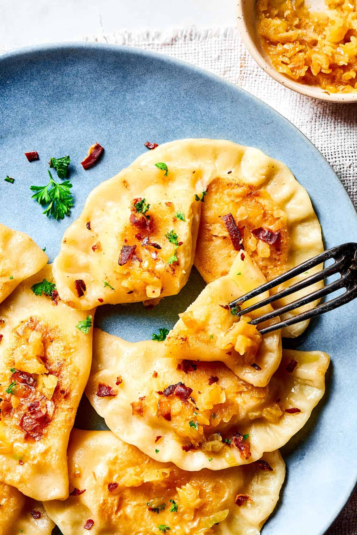 A fork piercing a bite-sized piece of a pierogi.