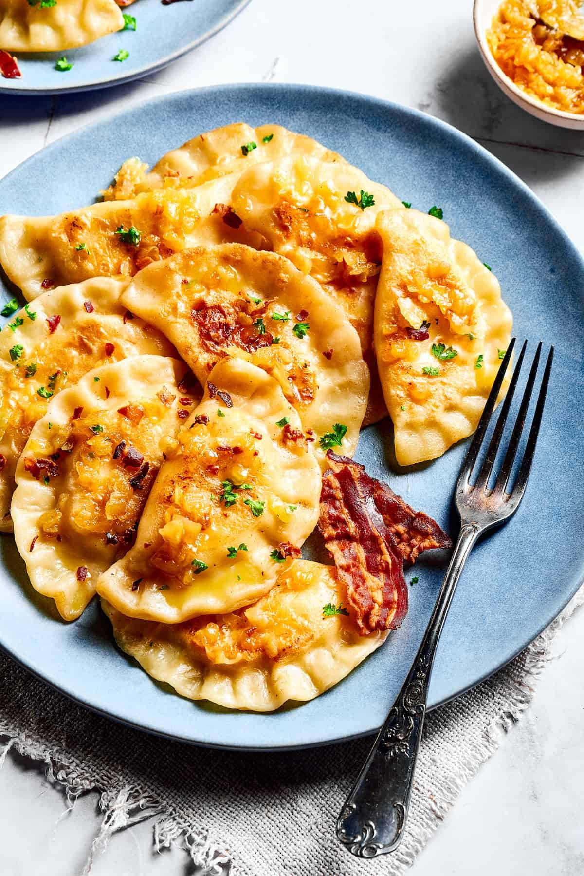 Homemade potato-filled dumplings on a blue plate with a fork.