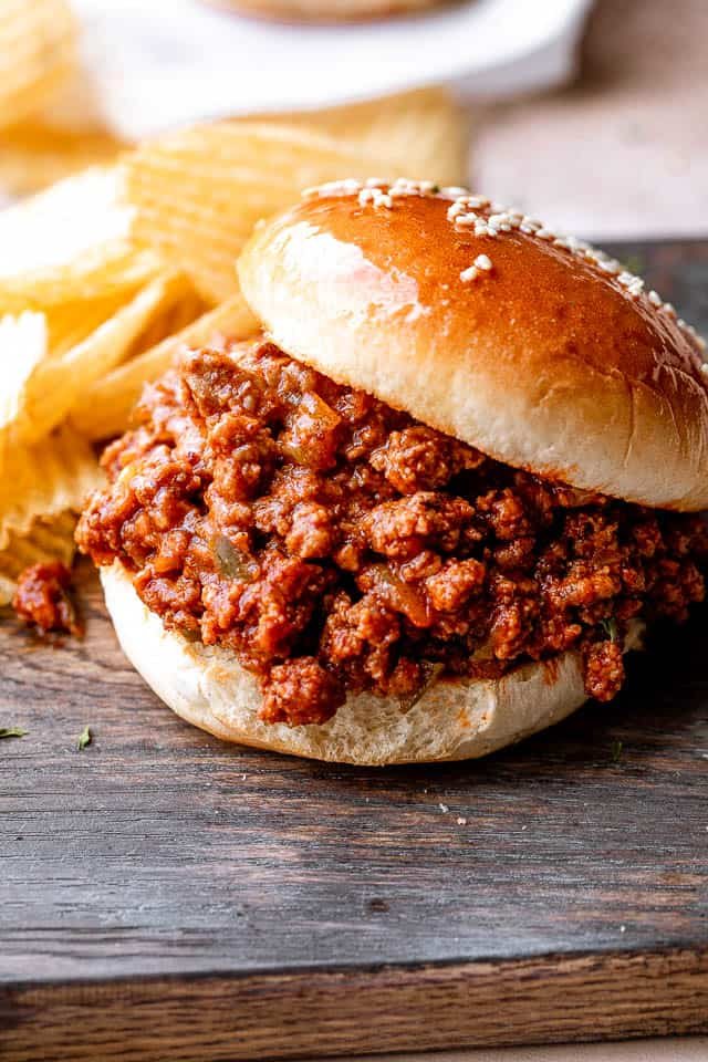 Close up of sloppy joe hamburger placed on a wooden board.