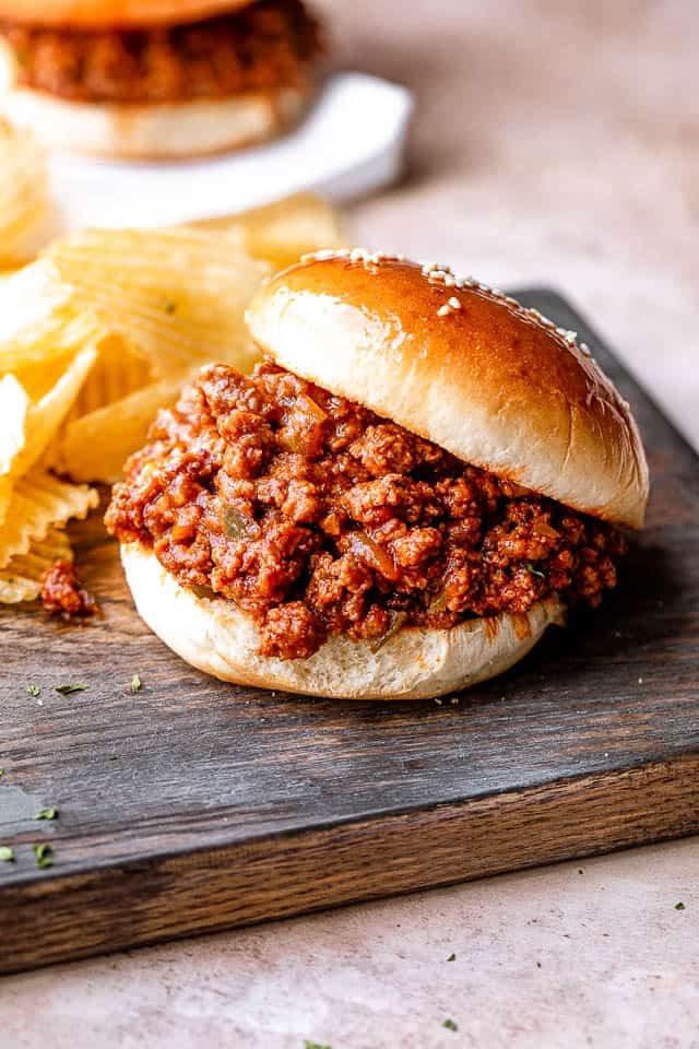 Sloppy joe on a bun with potato chips on the side.