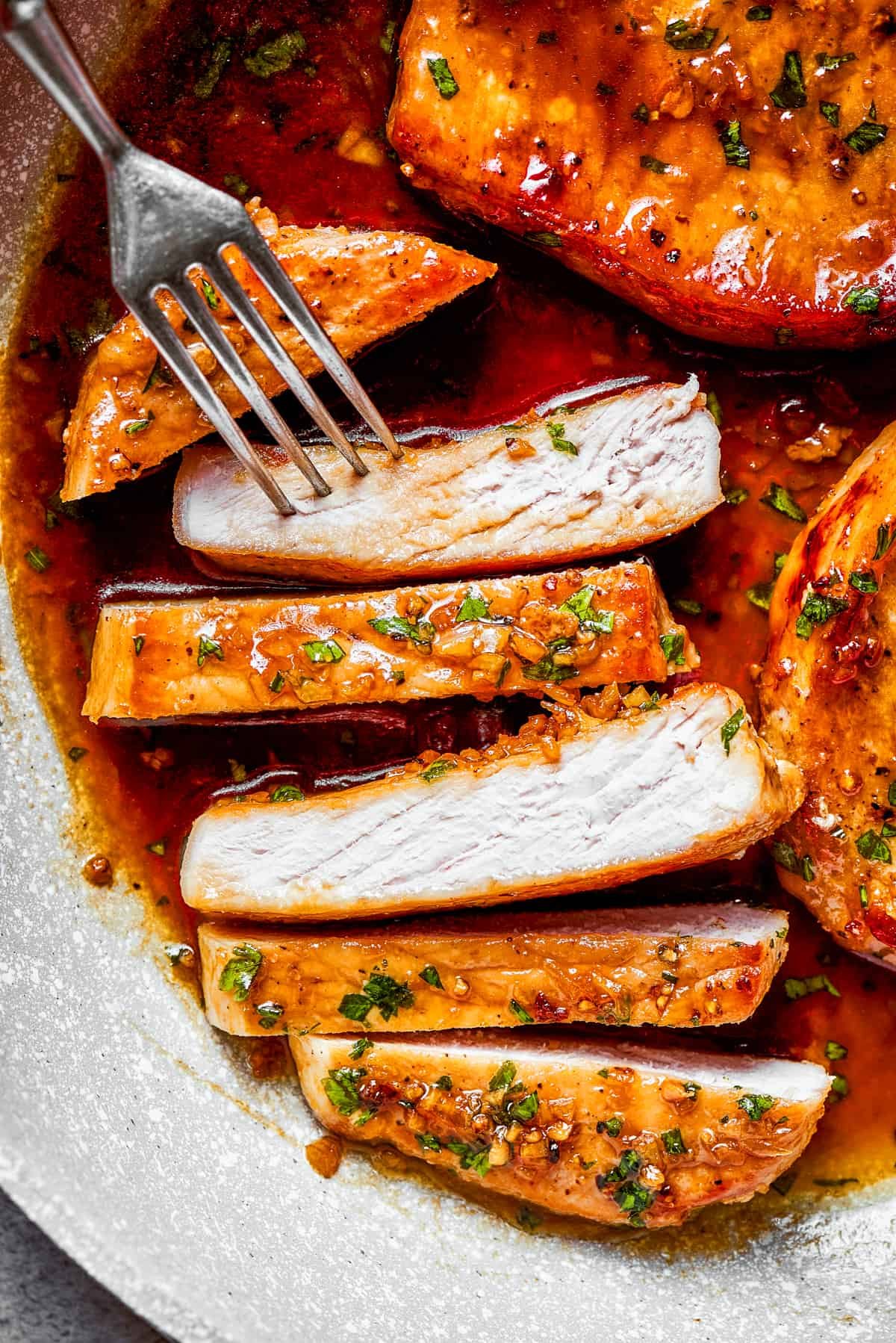Sliced pork chops with a fork reaching for a piece.