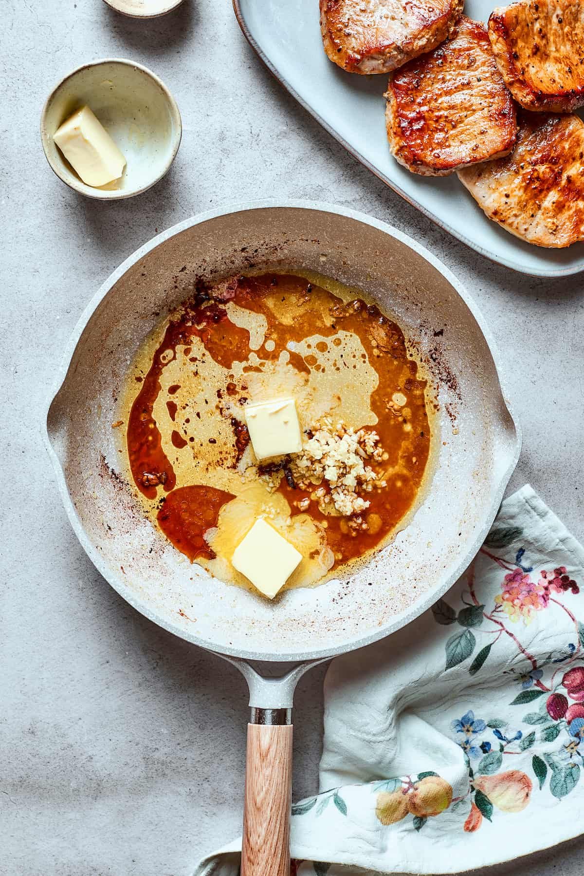 Butter melts in a white skillet.