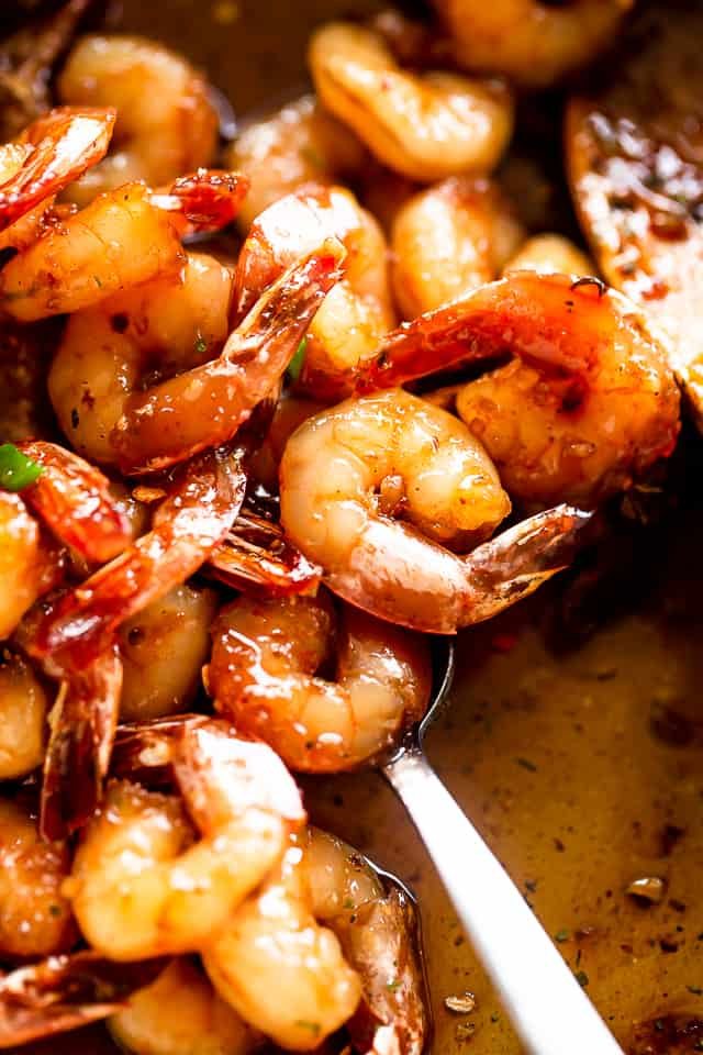 Using a spoon to stir garlic shrimp.