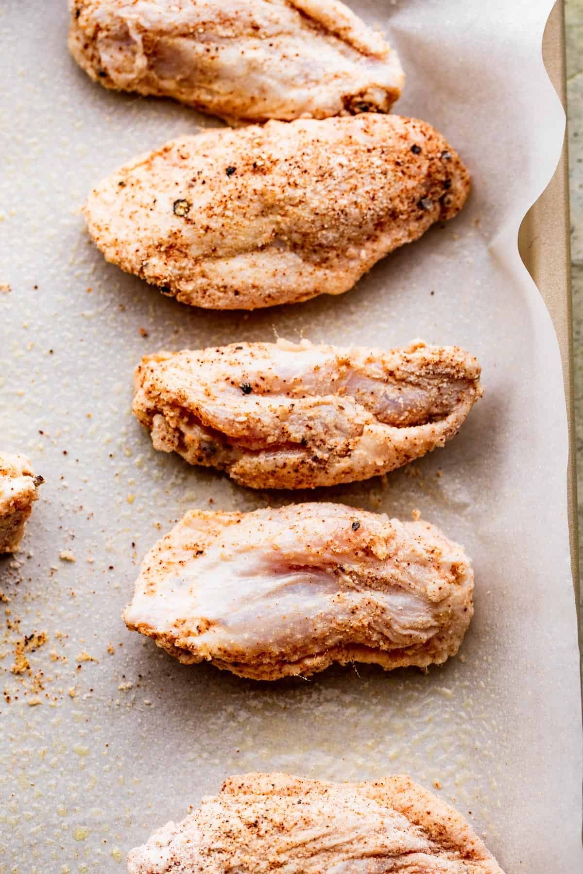 raw wings set on a parchment lined baking sheet.