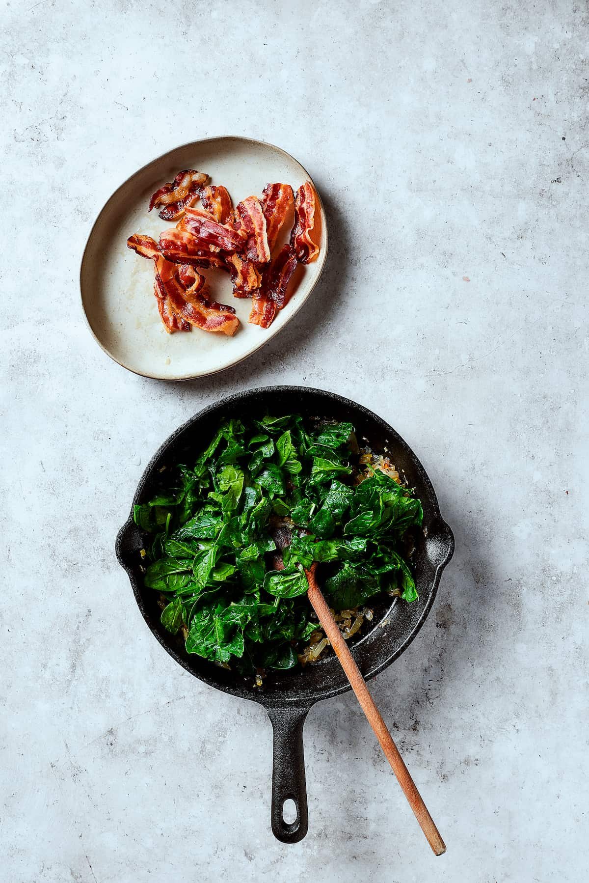 Cooking spinach in a skillet with onion an garlic.