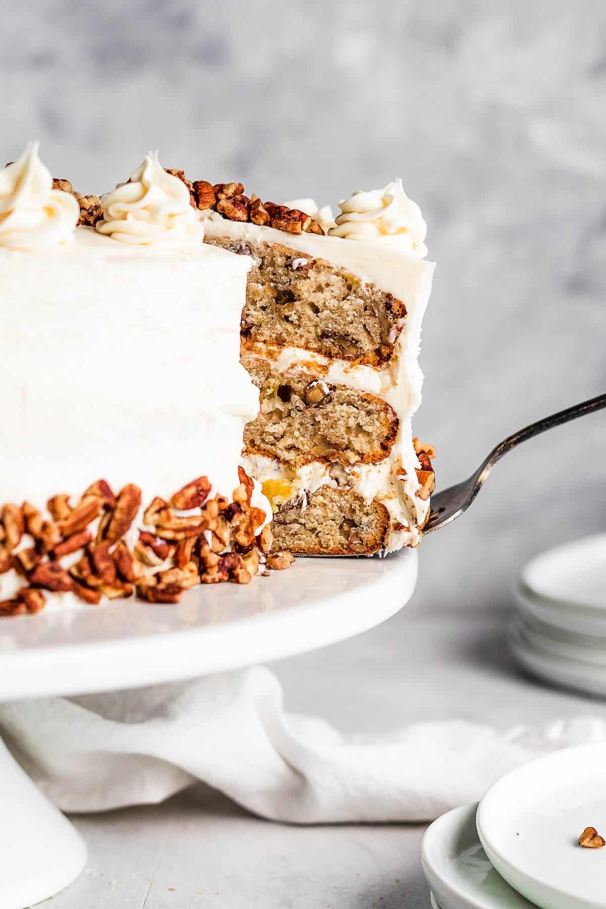 A Slice of Frosted Layer Cake Being Lifted From a Cake Stand