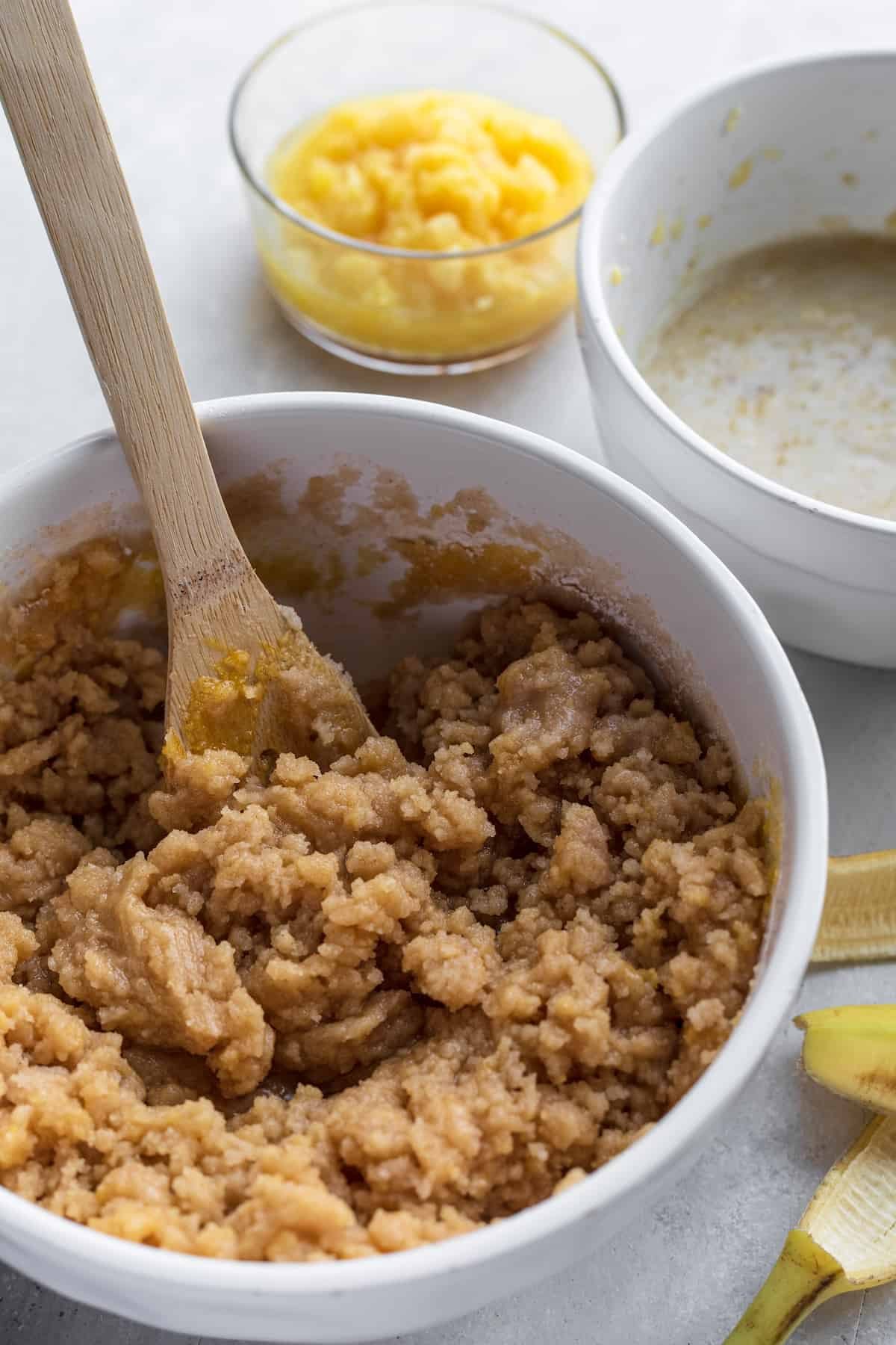 Hummingbird Cake Batter in a White Bowl on a Countertop Next to a Banana Peel