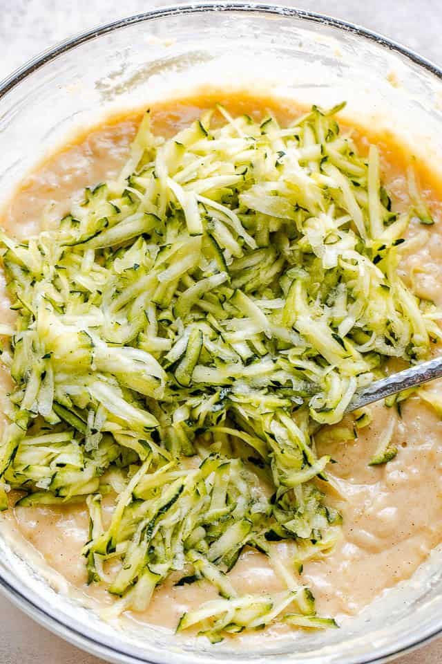 glass mixing bowl with shredded zucchini batter for bread
