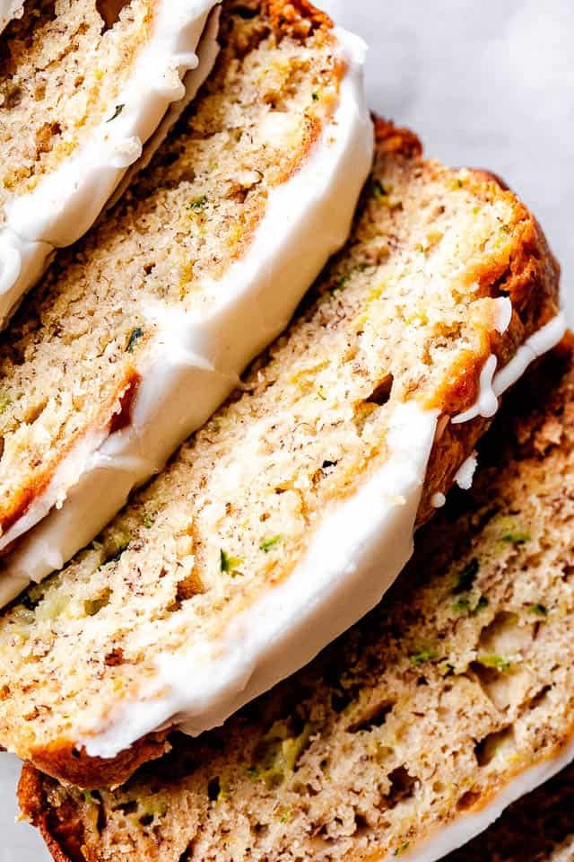 top shot of zucchini bread slices topped with cream cheese frosting