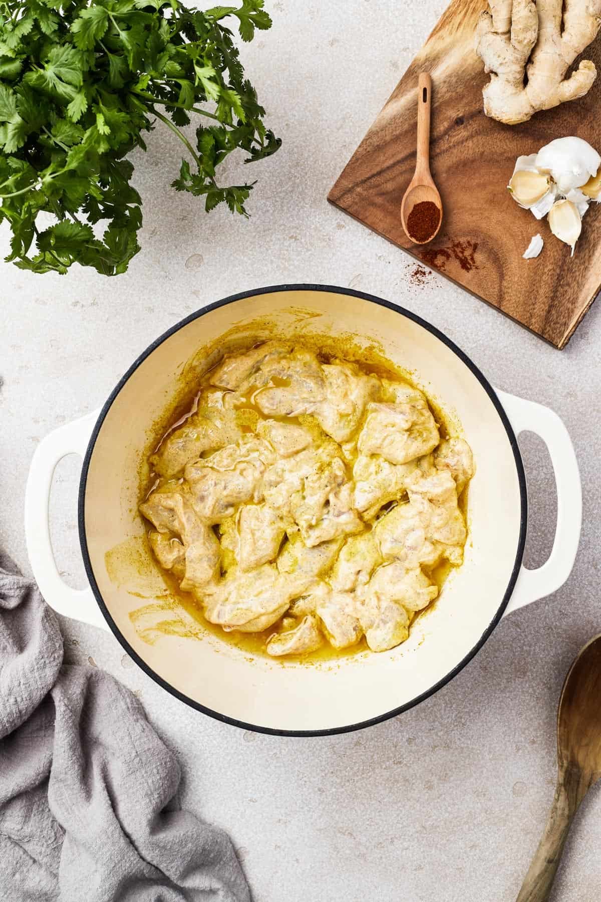 Chicken cooking in a yellow, creamy sauce.