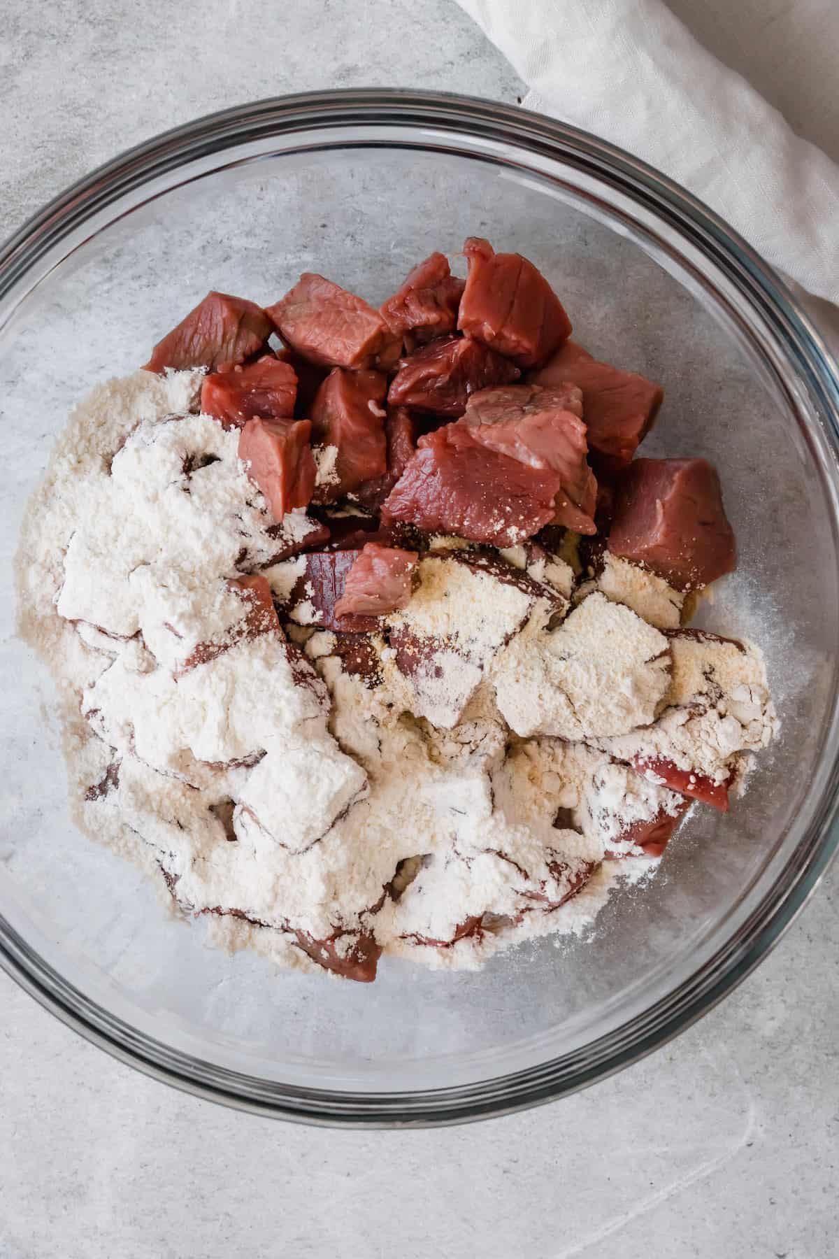 A Glass Bowl Holding the Beef and Flour Mixture