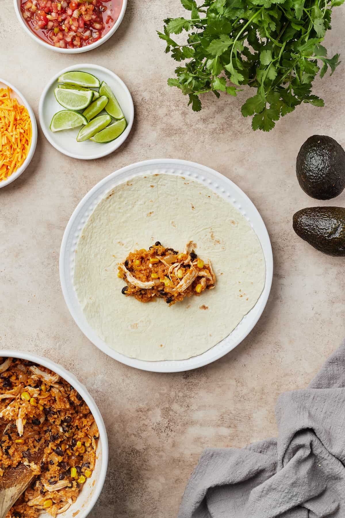 A tortilla on a plate, with burrito filling in the center.