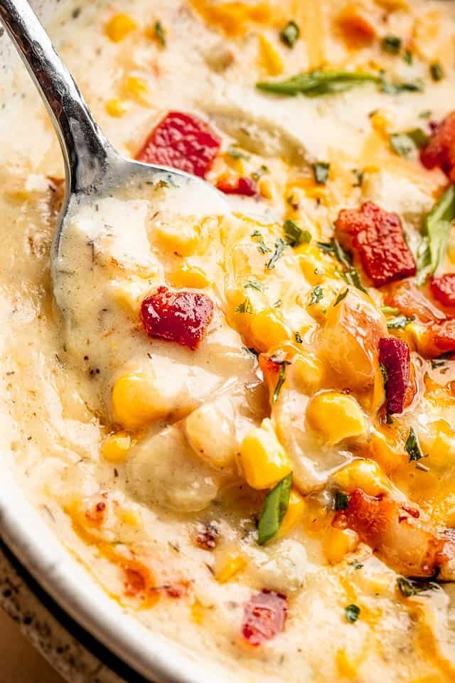 up close shot of a spoon inside creamy corn chowder with bacon