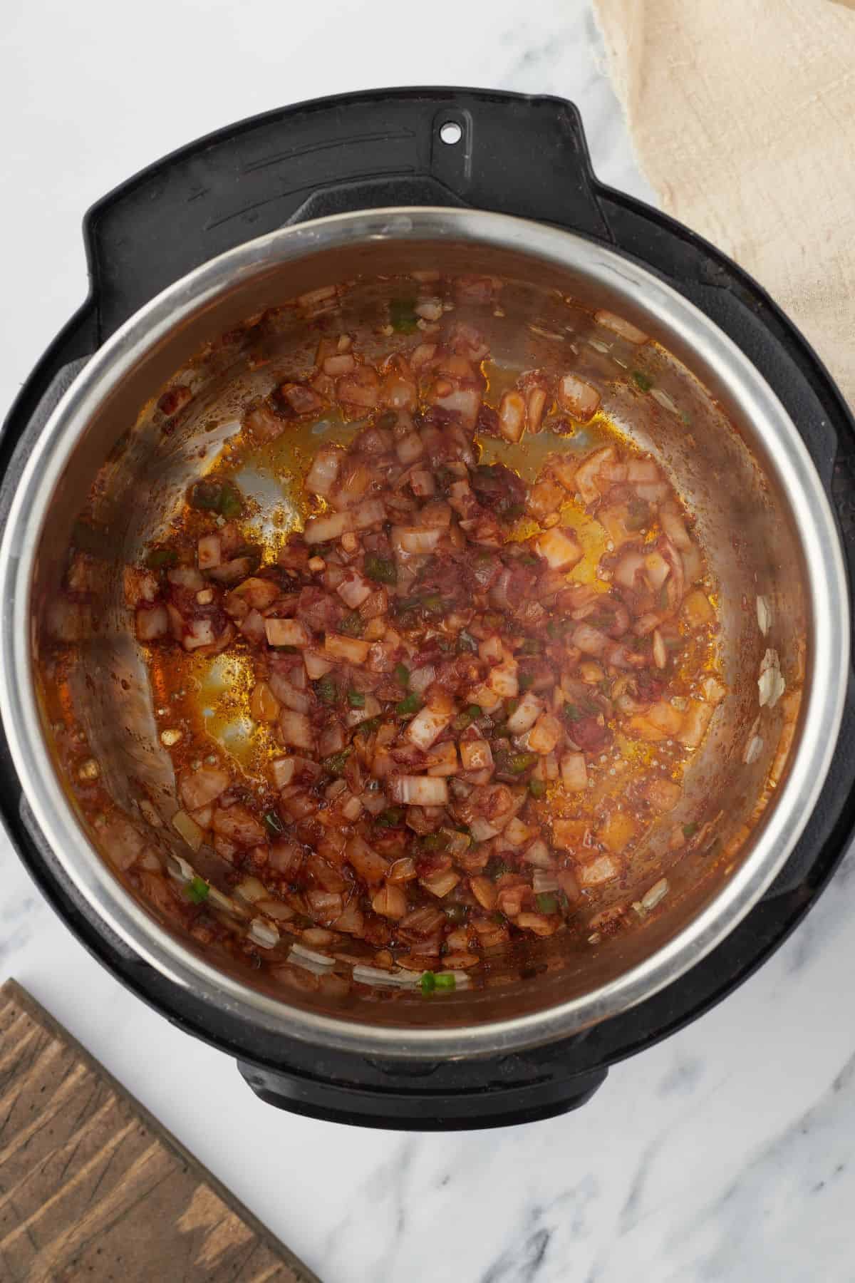 Overhead shot of an Instant Pot with vegetables and tomato paste sauteing.
