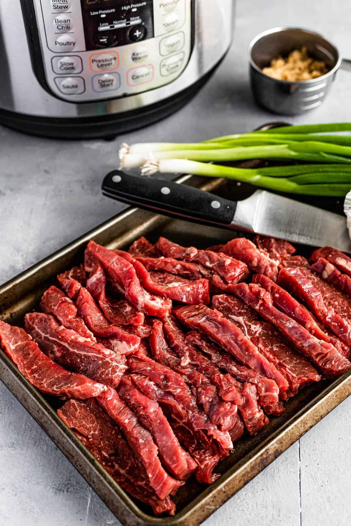Green Onions, Garlic, Soy Sauce, Slices of Flank Steak and the Rest of the Ingredients on Two Different Baking Sheets